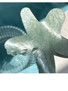 Detail of mint green starfish hair claw clip with golden glitter and acetate texture