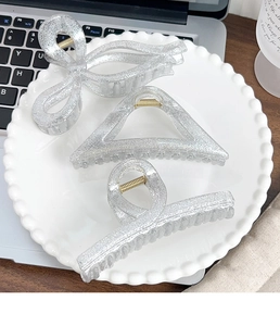 Three-piece silver glitter hair claw clips set including bow and geometric shapes in a ceramic tray