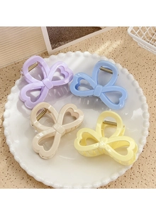 Détail de quatre pinces à cheveux pastel violettes, bleues, beige et jaunes sur une assiette