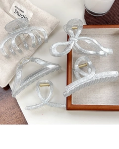 Detail view of five assorted silver glitter hair claws in various geometric shapes