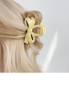 Pince à cheveux élégante en forme de nœud crème sur cheveux blonds, style minimaliste