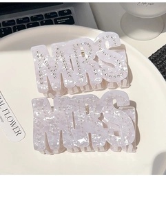 Détail de pinces à cheveux MRS en acrylique avec perles et strass sur marbre