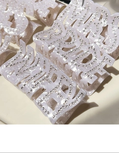 Détail du grand pince à cheveux avec lettres en strass brillants et texture perlée