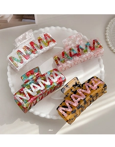Flat lay of four marble-patterned hair claws with MAMA letter design on a pearl plate