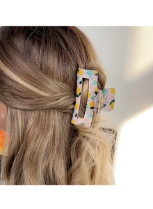 Detail of square pink hair claw clip with lemon pattern worn on wavy hair