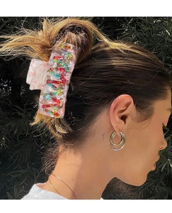Detail of large colorful patterned hair claw clip on female hairstyle with outdoor background