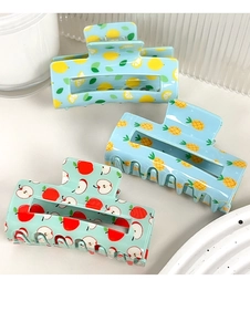 Detailed view of hollow rectangular hair claws with lemon, pineapple and apple patterns