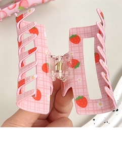 Close-up of pink checkered hair claw clip with red strawberry and floral patterns