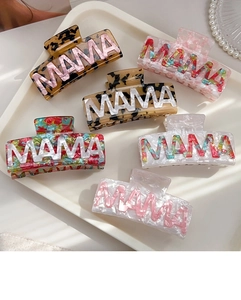 Detail view of acrylic hair claws with MAMA lettering in various marbled textures