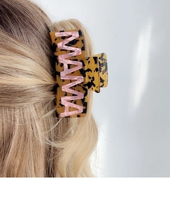 Detailed view of a tortoiseshell claw clip featuring pink MAMA lettering on a woman's hair