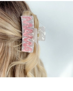 Detail of a large pink marble acetate hair claw clip worn on blonde hair for daily styling