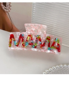 Macro detail of MAMA acetate hair claw clip with colorful letters on white background