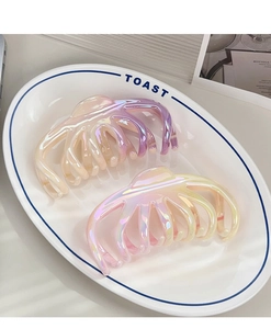 Macro detail of octopus-style gradient hair claws with iridescent finish on a ceramic plate