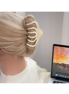 Close-up of a large cream pearlescent shark hair claw clip in a stylish side-back hairstyle