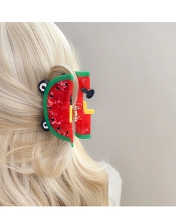 Detail der kreativen Melonen-Haarklammer aus Acetat in Rot und Grün auf blondem Haar