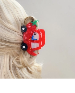 Detail der kreativen roten Auto-Haarklammer mit Marmortextur auf blondem gewelltem Haar