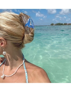 Détail de la pince à cheveux requin bleu sur chignon français avec plage tropicale