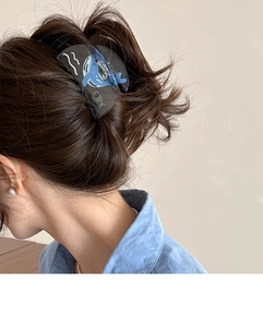 Détail d'une pince à cheveux requin de style océan avec motifs de vagues sur cheveux