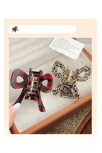 Detailed close-up of red plaid and leopard print bow hair claws on a jewelry tray
