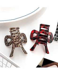 Detail view of leopard print and red plaid bow hair clips with a high-gloss finish