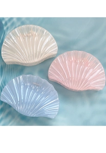 Detailed close-up of shell-shaped hair claws in pearlescent white, pink, and blue