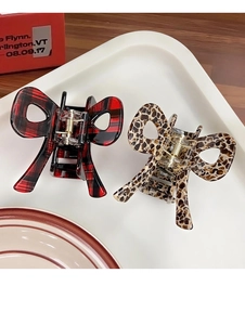 Close-up of red plaid and leopard print acetate bow hair claws on a decorative tray