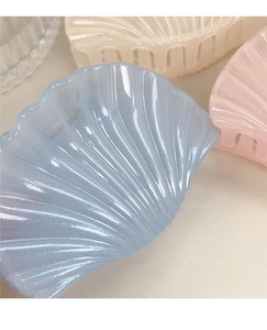 Macro detail of shell-shaped hair claw clips in pastel blue, pink and cream colors