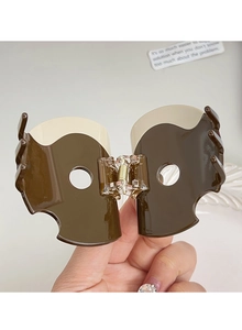 Detail view of brown and beige acetate hair claw clip showing inner spring and teeth