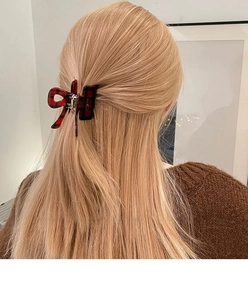 Detail view of red plaid bow hair claw clip styled on blonde hair for a cozy winter look