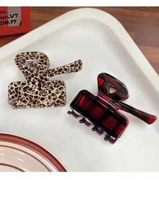 Detail view of leopard print and red plaid acetate claw clips in a white tray