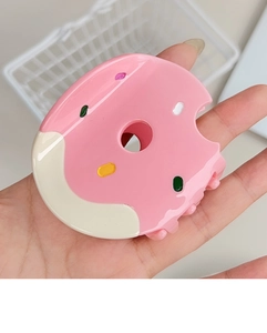 Detail of donut-shaped hair claw clip with pink icing and colorful sprinkles design