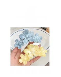 Detail showing marble texture on oversized floral hair claws in light blue and yellow