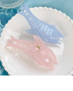 Detail of dolphin-shaped jelly shell hair claw clips in pink and light blue colors