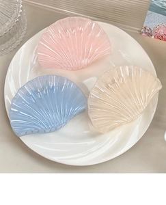 Macro shot of seashell hair claws in pink, blue, and beige with pearlescent resin finish