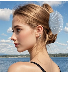 Blue shell-shaped claw clip shown in a stylish outdoor hairstyle on a model