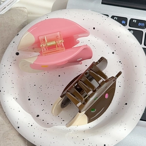 Pink and brown donut-shaped acetate hair claws on a ceramic tray in an office setting