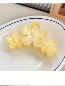 Detail of yellow floral hair claw clip with marble texture and resin finish
