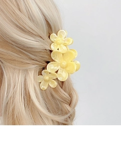 Detail of yellow flower hair claw clip styling on blonde wavy hair for elegant hairstyles
