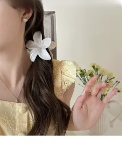 Large pearlescent flower hair claw clip styled on long dark wavy hair for elegant look