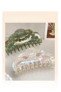 Detail of dark green marble and pearlescent white cloud-shaped hair claw clips