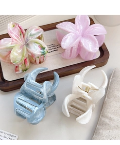 Group shot of floral and marble patterned acetate hair claws on a wooden tray