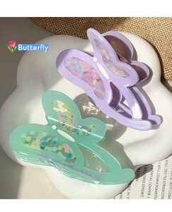 Detail of lavender and mint green hollow butterfly hair claws with confetti details