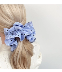 Detailed view of oversized blue striped bow hair tie with heart print on blonde hair