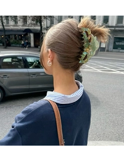 Detail view of a large translucent floral claw clip in iridescent green on a model's hair