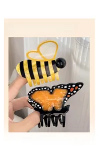 Détail des pinces à cheveux abeille et papillon en acétate pour des coiffures demi-attachées