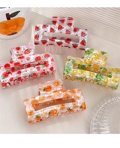 Dettaglio dei mollettoni quadrati in acetato con stampe di frutta colorata per l'estate