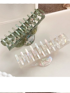 Detail view of large matte green and pearlescent white PVC shark hair clips for women