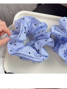 Detailed view of blue striped fabric scrunchie with black heart pattern on a white tray