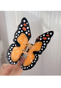 Vue détaillée d'une grande pince à cheveux papillon aux motifs de marbre orange