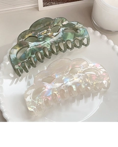 Detail of large marble green and pearlescent white hair claw clips in a ceramic dish